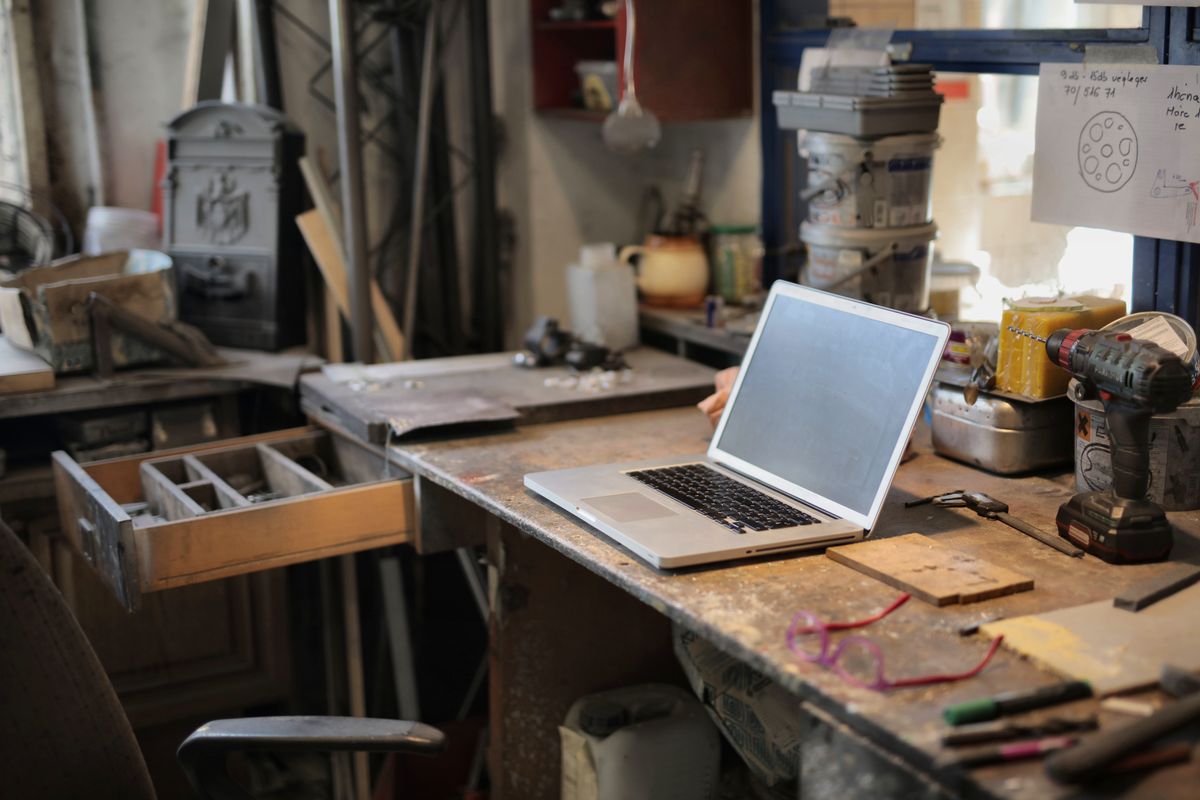A laptop open on a workbench in a small workshop