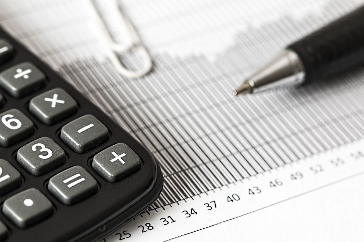 A calculator and pen resting on a printed financial report