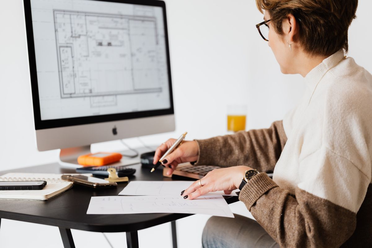 A person reviewing plans at a desk with a computer